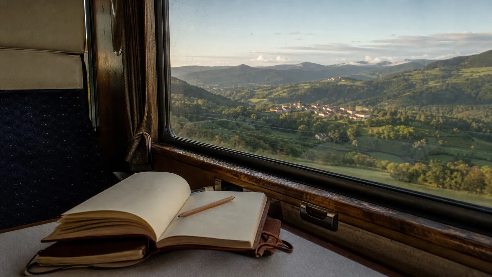 Carnet ouvert devant le paysage aperçu depuis un train