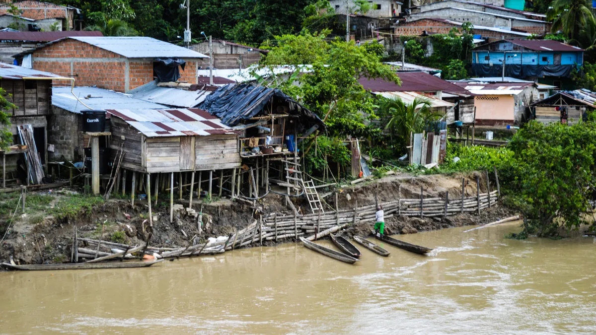 Maisons sur pilotis et pirogues au bord d'un fleuve tropical